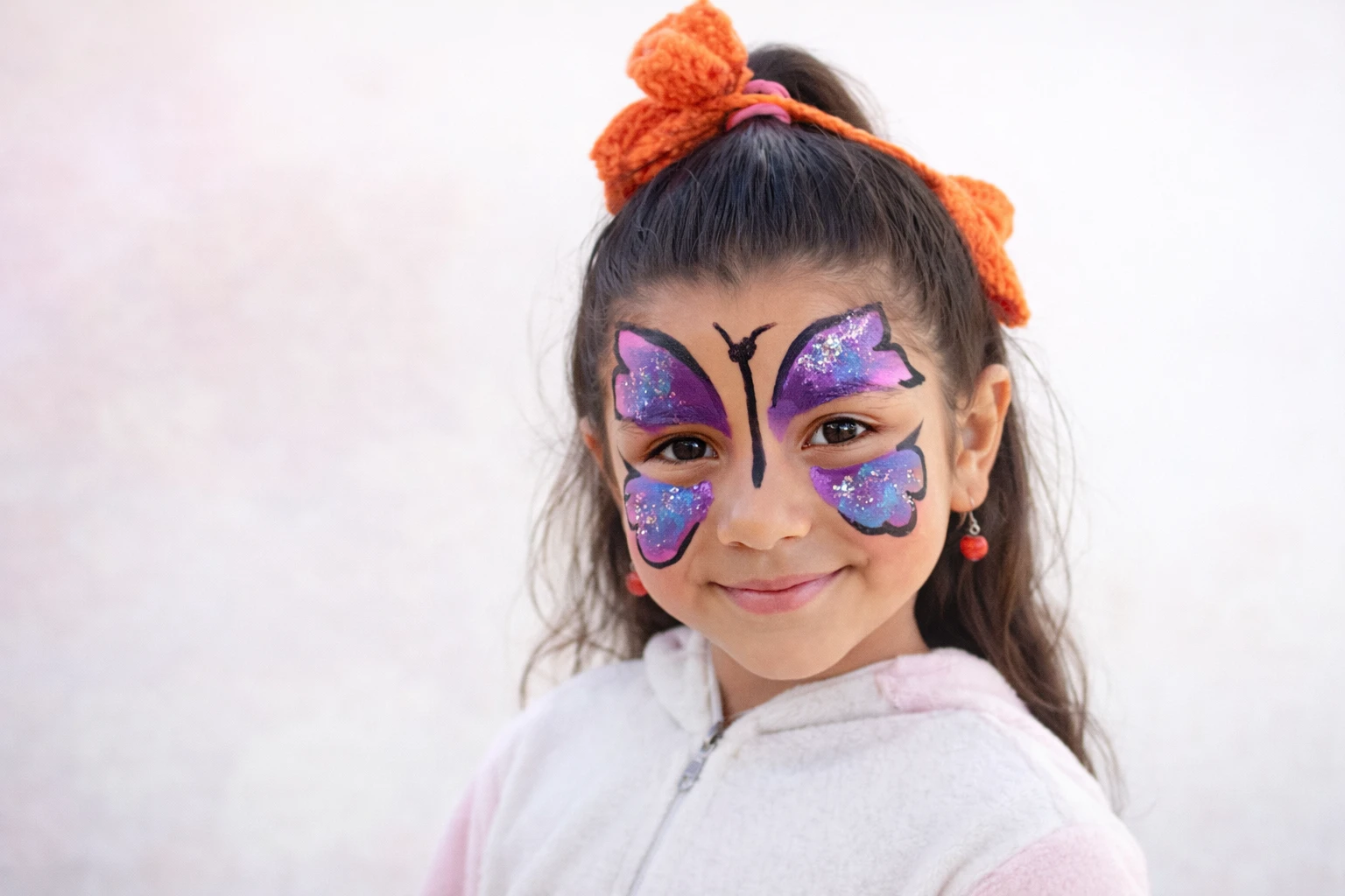 Niña con maquillaje de mariposa violeta con brillos